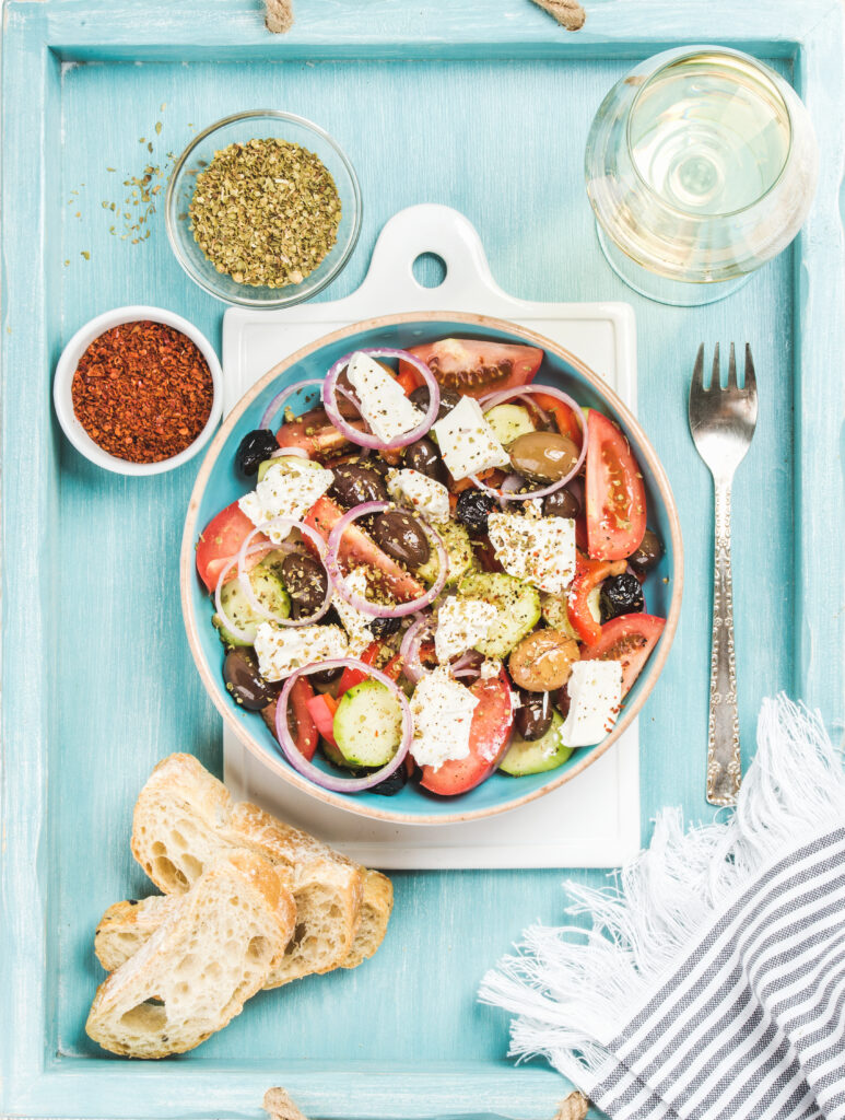 Greek salad with bread, oregano, pepper and glass of wine